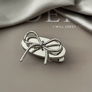 Detailed close-up of a silver hollow bow hair clip with high-polish mirror finish