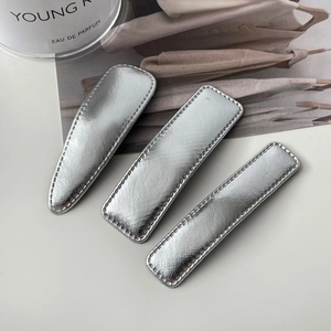 Detail showing a set of three silver textured metal hair clips with fine stitching edges
