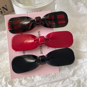 Three-piece acetate bow hair clips in red, black, and plaid patterns on display card
