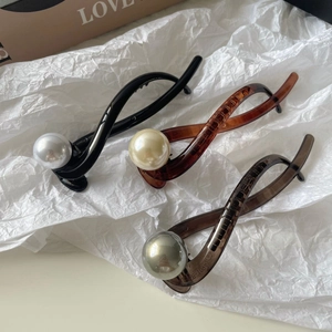 Three vintage pearl hair clips in black, amber, and grey with a twisted cross design