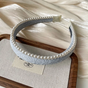 Close-up of light blue jacquard headband featuring a row of elegant white round pearls