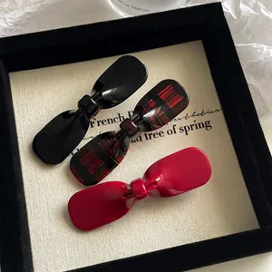 Elegant acetate bow hair clips in black, wine red, and plaid patterns on display card