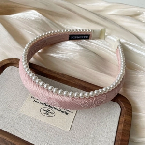 Detailed shot of handmade pink satin headband with white faux pearls on a tray