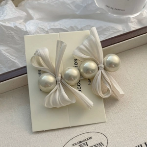 Détail de pinces à cheveux à nœud en satin ivoire avec perles sur carte de vente