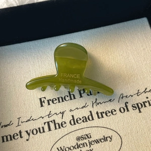 Détail macro d'une pince à cheveux en acétate vert avocat avec logo doré fait main