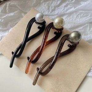 Vintage pearl twisted hair clips in black, amber, and grey on a rustic paper background