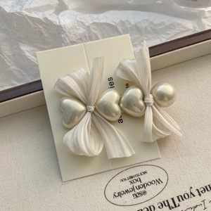 Détail de la barrette à nœud en tissu crème avec perles en cœur sur plateau élégant