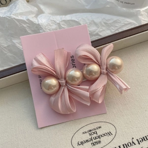 Détail de nœuds à cheveux en satin rose avec perles sur carte de présentation