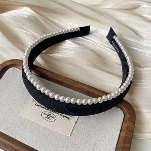 Detail of handmade black fabric headband with faux pearls and quality textile label