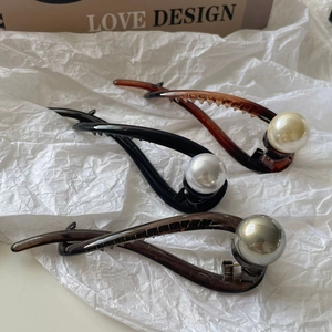 Detailed set of twisted banana hair clips with pearls in amber, black, and smoke grey
