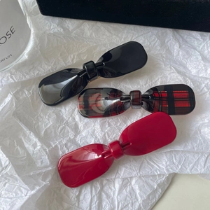 Close-up of three acetate bow hair clips in glossy black, red and checkered patterns