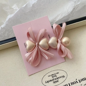 Détail d'une pince à cheveux à nœud rose avec cœurs en perles sur carte artisanale