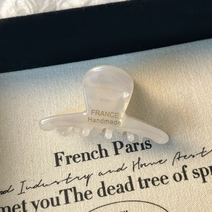 Gros plan d'une petite pince à cheveux en acétate avec inscription France Handmade