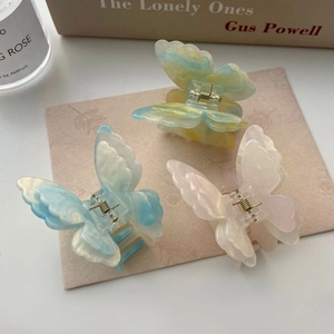 Trois pinces à cheveux papillon dégradées bleues, jaunes et roses sur fond élégant
