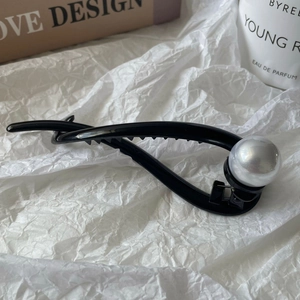 Detailed view of a sleek black twisted hair clip with a large white pearl accent