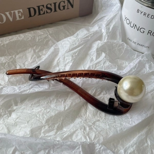 Close-up of amber resin twist hair clip featuring a large pearl and glossy finish