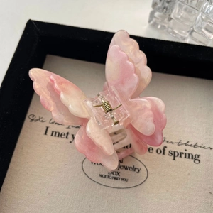 Gros plan détaillé d'une pince à cheveux papillon avec dégradé rose et nacre scintillante