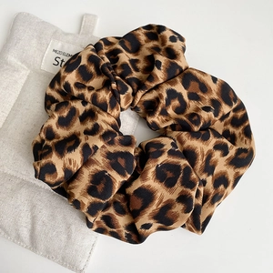 Detailed close-up of leopard print hair scrunchies with soft silky fabric texture