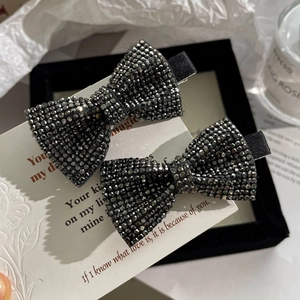 Close-up of sparkling black rhinestone bow hair clips on a professional white display card