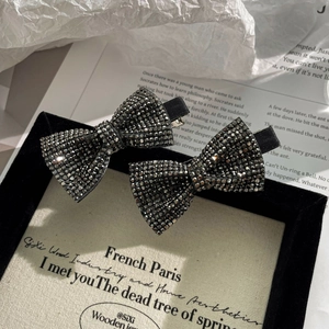 Detailed view of two sparkling rhinestone bow hair clips with elegant black finish