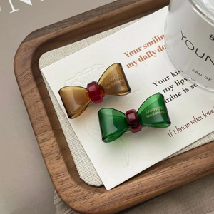 Detailed macro view of handmade acetate bow hair clips in amber and emerald finishes