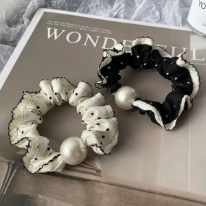 Detail view of lace-edged polka dot scrunchies set with a central large pearl decoration