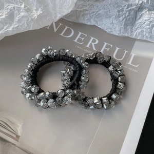 Elegant elastic hair ties set with grey crystal beads on minimalist magazine background