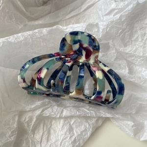 Détail d'une grande pince à cheveux en acétate marbré avec ressort puissant sur papier blanc