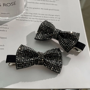 Close-up of elegant black bow hair clips with shimmering rhinestones and fabric texture