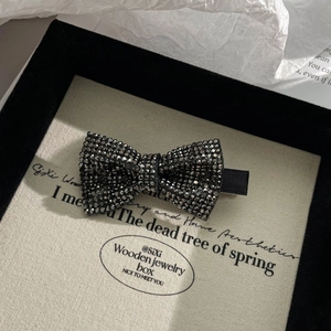 Close-up of bow hair clip featuring sparkling black rhinestones on a display card