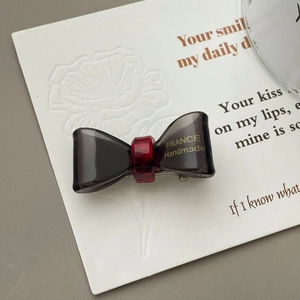 Detail showing transparent smoke grey bow hair clip with gold France Handmade logo