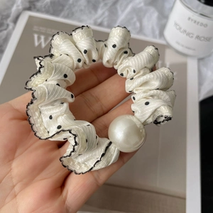 Polka dot hair scrunchie with lace trim and large pearl bead held by hand