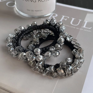 Detailed close-up of three crystal bead elastic hair ties set against a gray background