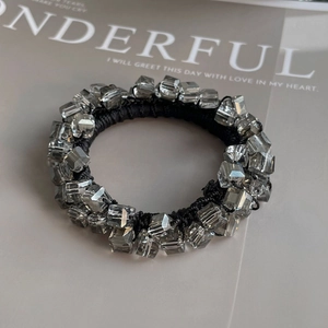 Macro shot of gray crystal beads on a black elastic hair tie over an aesthetic magazine