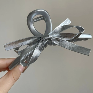 Detail of silver metallic claw clip with premium textured leather bow for hair styling