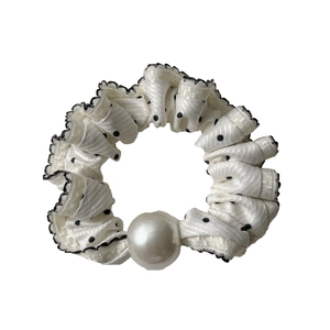 Polka dot hair scrunchie with lace trim and large pearl bead on a white background