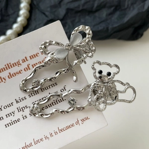 Détails de barrettes argentées papillon et ours avec strass sur une carte