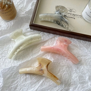 Set of four large acetate hair claws with marble and amber patterns in a premium gift tray