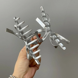 Close-up of a silver metal hair claw clip featuring a matte leather-textured bow design