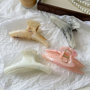 Set of four large marbled hair claws in cream, grey, and pink displayed on a white tray