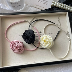 Detailed view of handmade satin rose chokers in pink black and white on elegant display