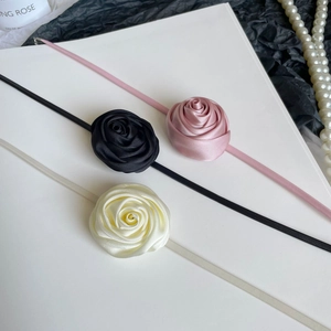 Three-color set of handmade satin rose chokers in pink black and white on elegant background