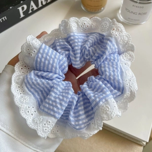 Détail d'un chouchou à rayures bleues et blanches avec bordure en dentelle brodée blanche