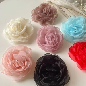 Détail de barrettes camélia en mousseline 3D déclinées en sept couleurs élégantes