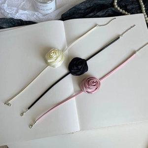 Detail view of handmade satin rose chokers with adjustable lobster clasp in three soft colors
