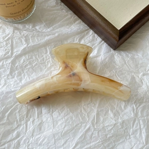 Macro shot of large marble-textured hair claw clip with amber and cream patterns