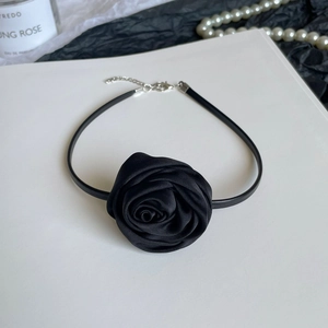 Detail of a black satin rose choker necklace with adjustable leather cord on a white base