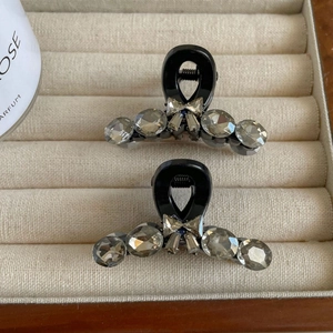 Détail de deux mini pinces à cheveux noires avec strass gris et petits nœuds