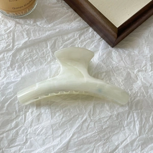 Detailed view of cream marble texture hair claw clip on aesthetic white textured background