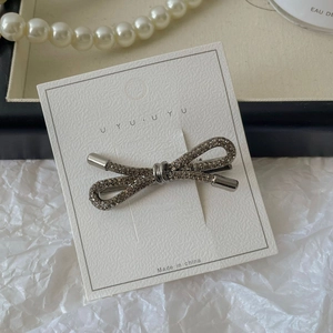 Detailopname van de strik haarclip met donkergrijze steentjes op een elegante achtergrond